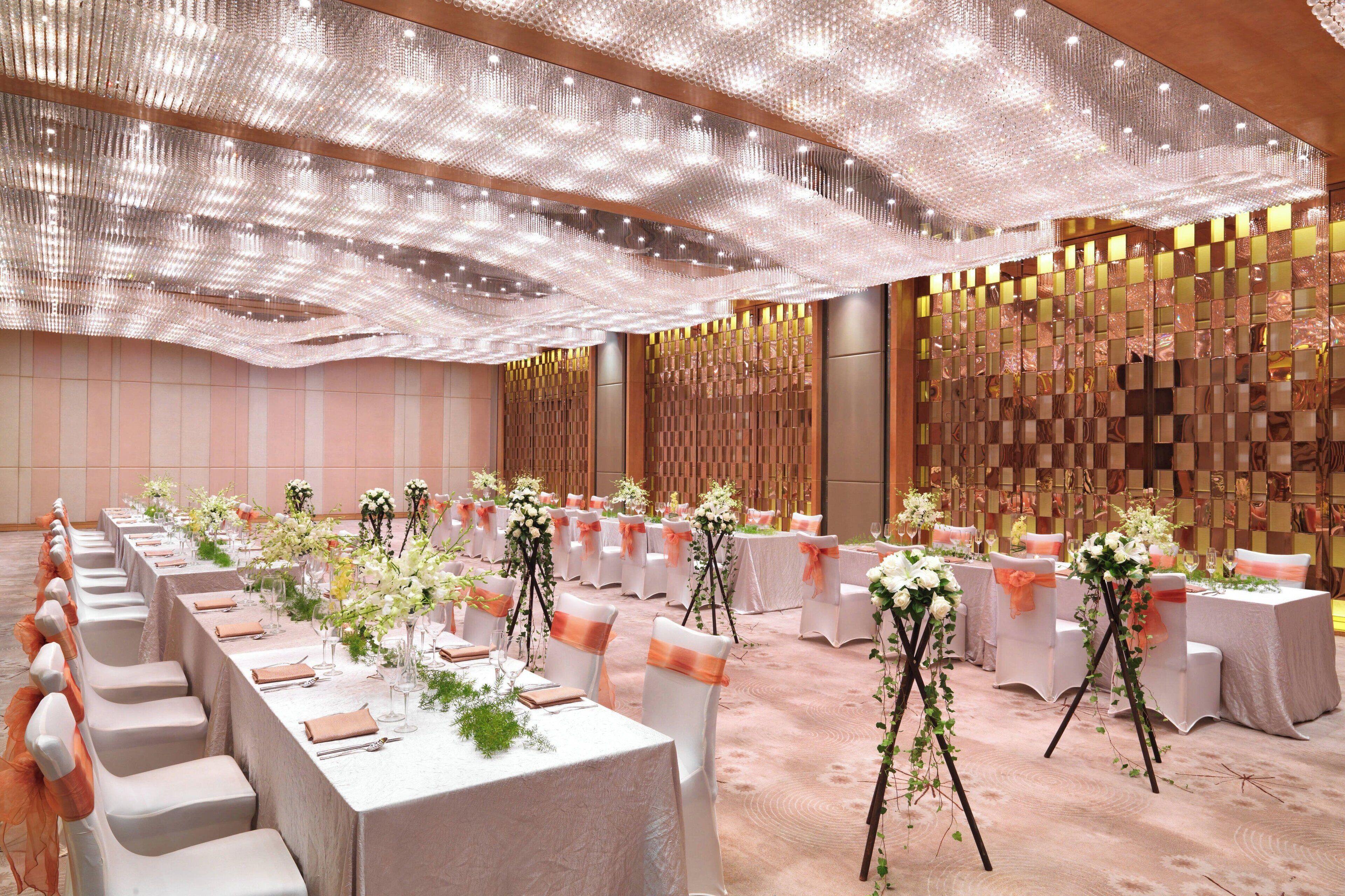 A banquet hall with long tables, white tablecloths, and floral centerpieces.