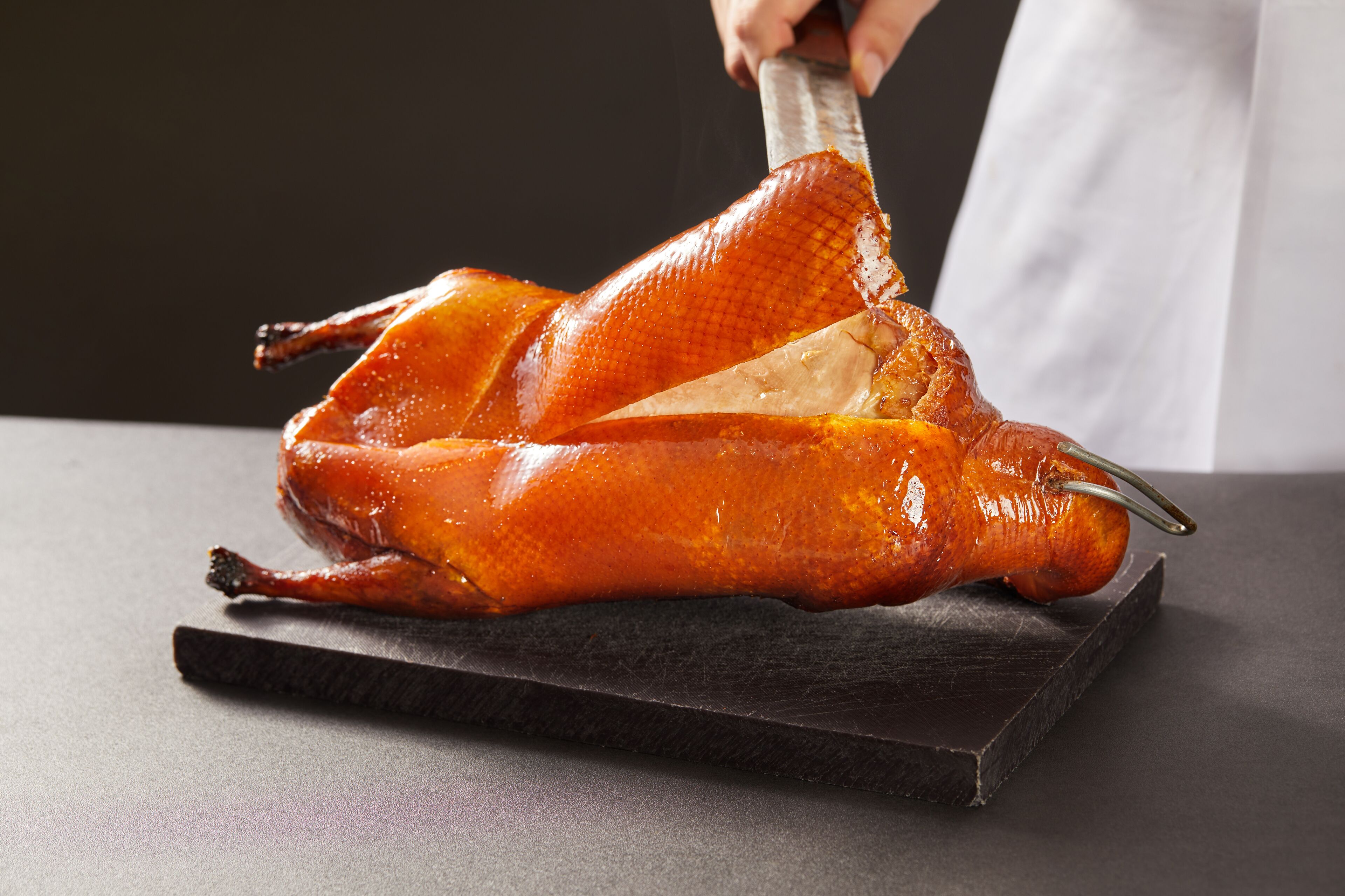 Un pato asado sobre una tabla de cortar oscura.