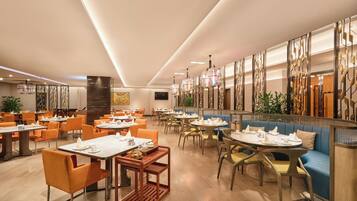 A modern restaurant with multiple dining areas, including booths and tables with chairs.