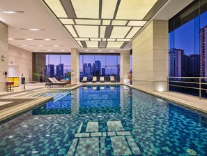 A modern indoor swimming pool with a city view, tiled floor, and lounge chairs. - Four Points® by Sheraton Guangzhou Financial City, Tianhe (Guangzhou)