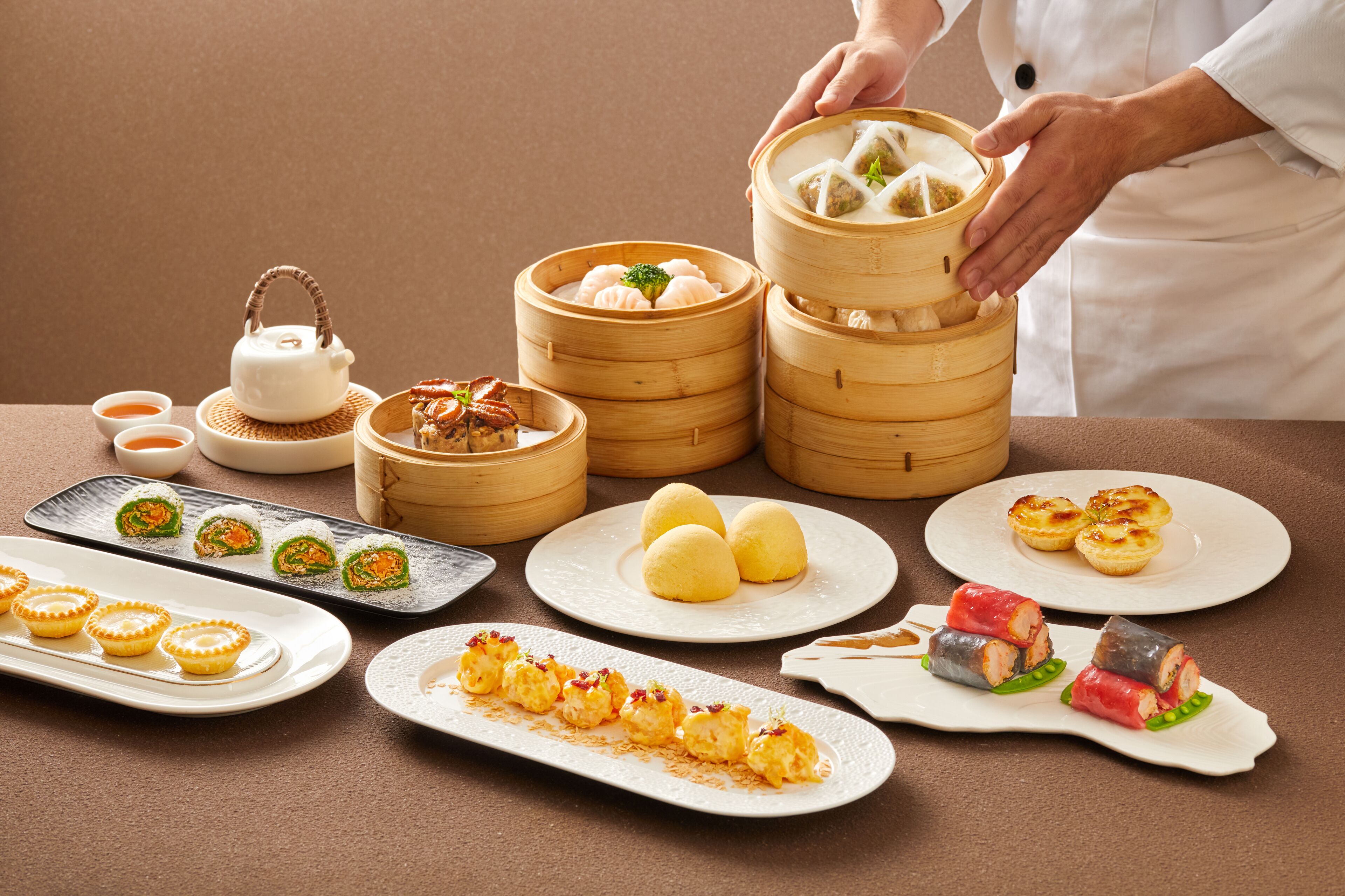 Verschiedene asiatische Gerichte, darunter Teigtaschen und Sushi, sind auf einem Tisch angerichtet.