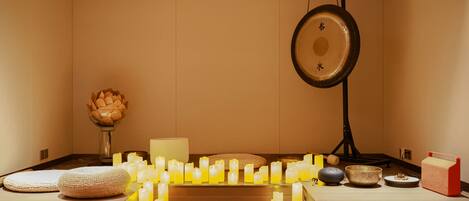 Una habitación con un altar central decorado con velas, un gong colgante y una cesta tejida.