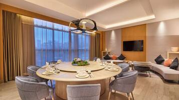 A modern dining area with a round table, chairs, and a central light fixture.