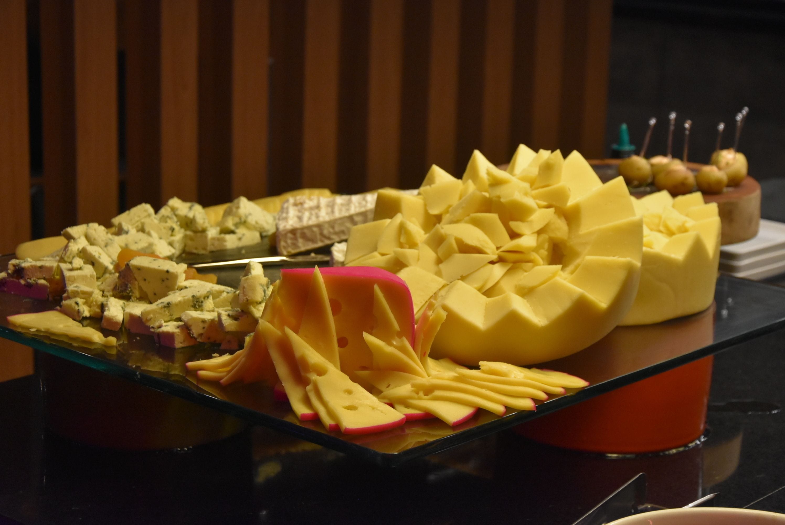 Un plateau de service en verre, sur lequel sont disposés différents fromages et fruits.
