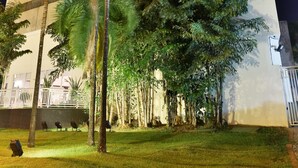 Un hotel con fachada moderna, un letrero llamativo y un césped bien cuidado con palmeras.