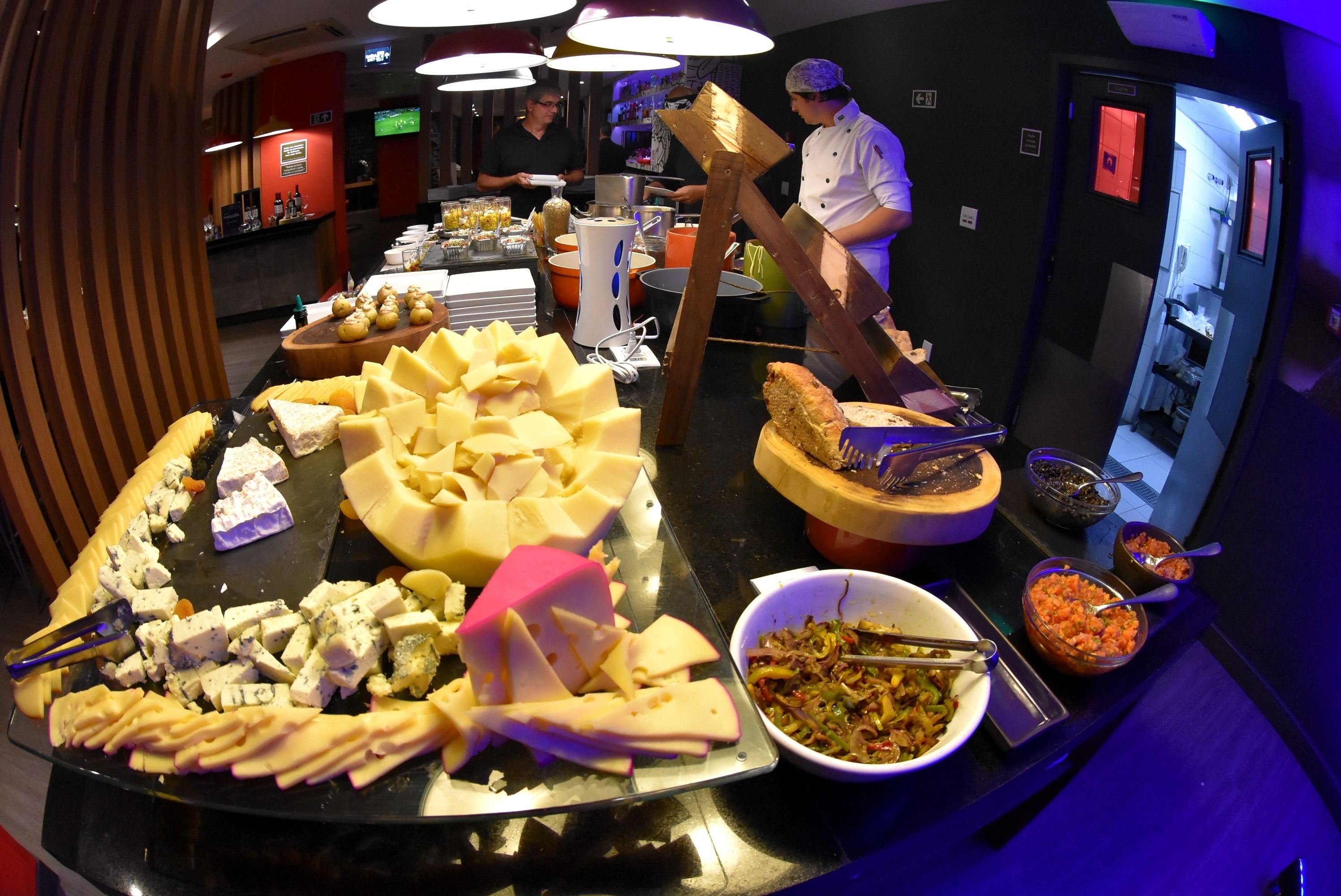 A buffet with various cheeses, meats, and vegetables.