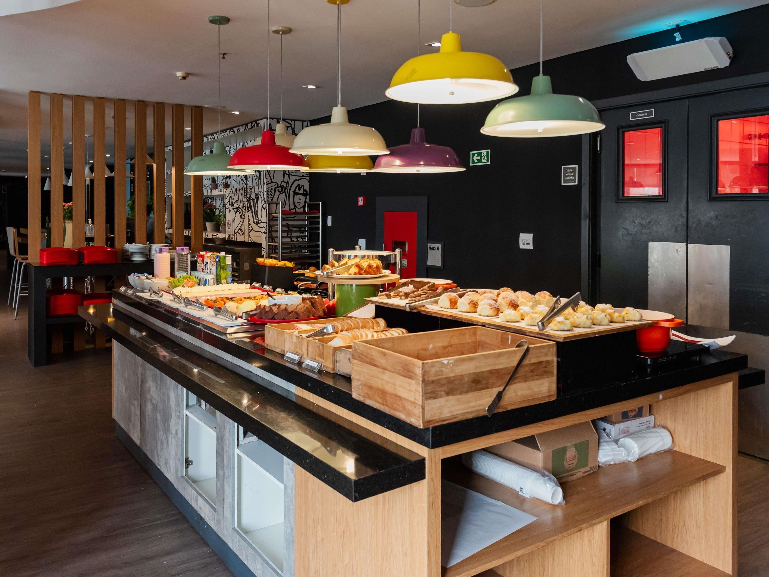 A buffet area with a variety of food items and colorful pendant lights.