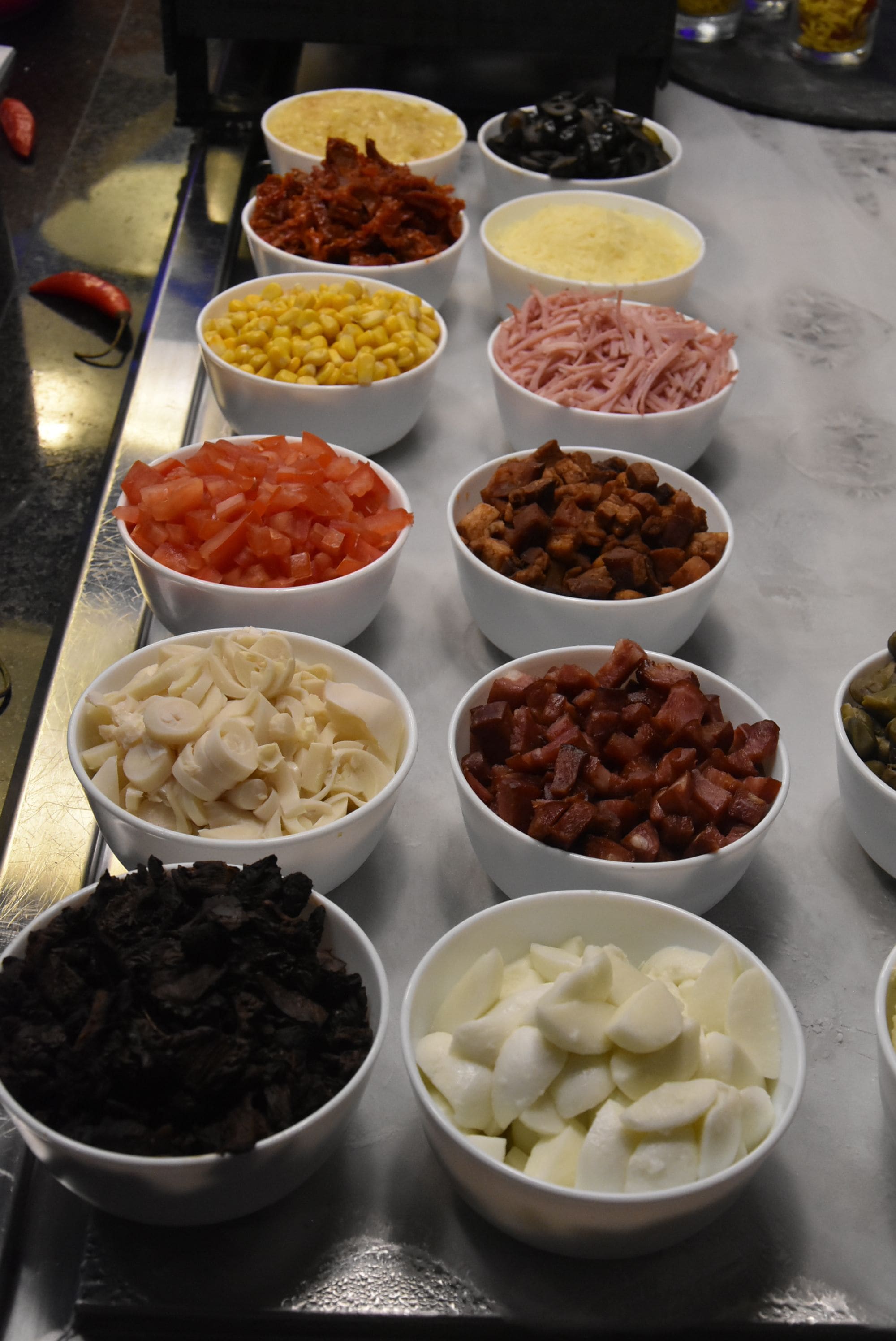 A variety of food items in bowls on a metal table.