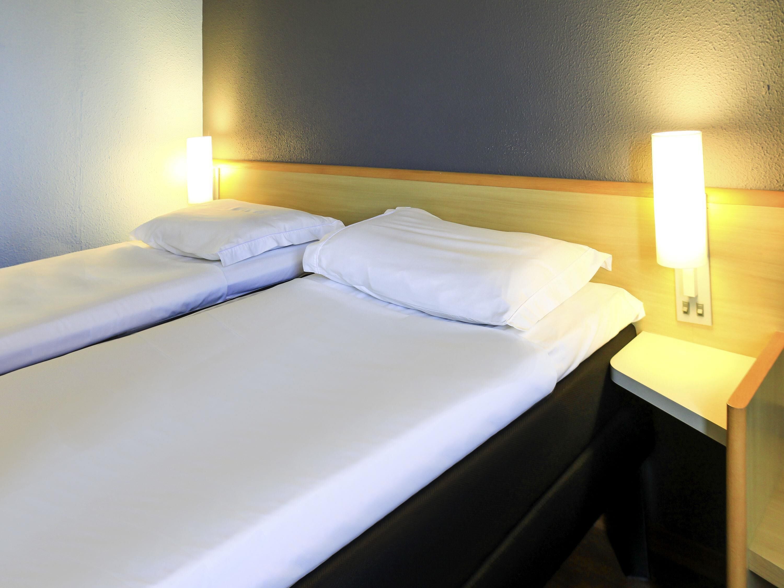 Un lit double avec du linge de lit blanc et deux lampes de chevet.