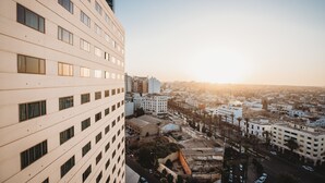 Un edificio moderno con múltiples ventanas y vistas a un paisaje urbano al atardecer.