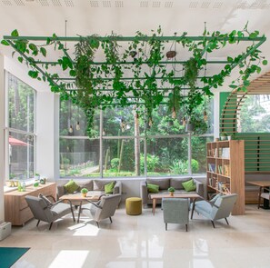 A modern interior with large windows, a green plant installation, and a wooden bookshelf. - ibis Casablanca City Center (Casablanca)