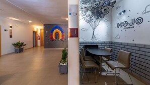A modern interior with a reception area, a mural, and a coworking space with tables and chairs. - Ibis Manaus Distrito Industrial (Manaus)