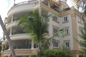 A multi-story building with balconies, palm trees, and a clear sky. - White Sands Beach Condos (St. Lawrence Gap)