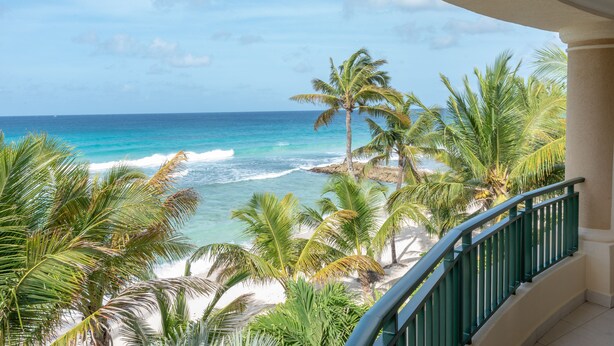 A balcony with a view of a beach and ocean. - White Sands Beach Condos (St. Lawrence Gap)