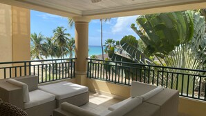 A balcony with wicker furniture and a view of the beach and palm trees. - White Sands Beach Condos (St. Lawrence Gap)