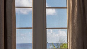 A window with a view of the ocean and palm trees. - White Sands Beach Condos (St. Lawrence Gap)