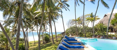 Una piscina al aire libre, sombrillas, sillones reclinables de piscina
