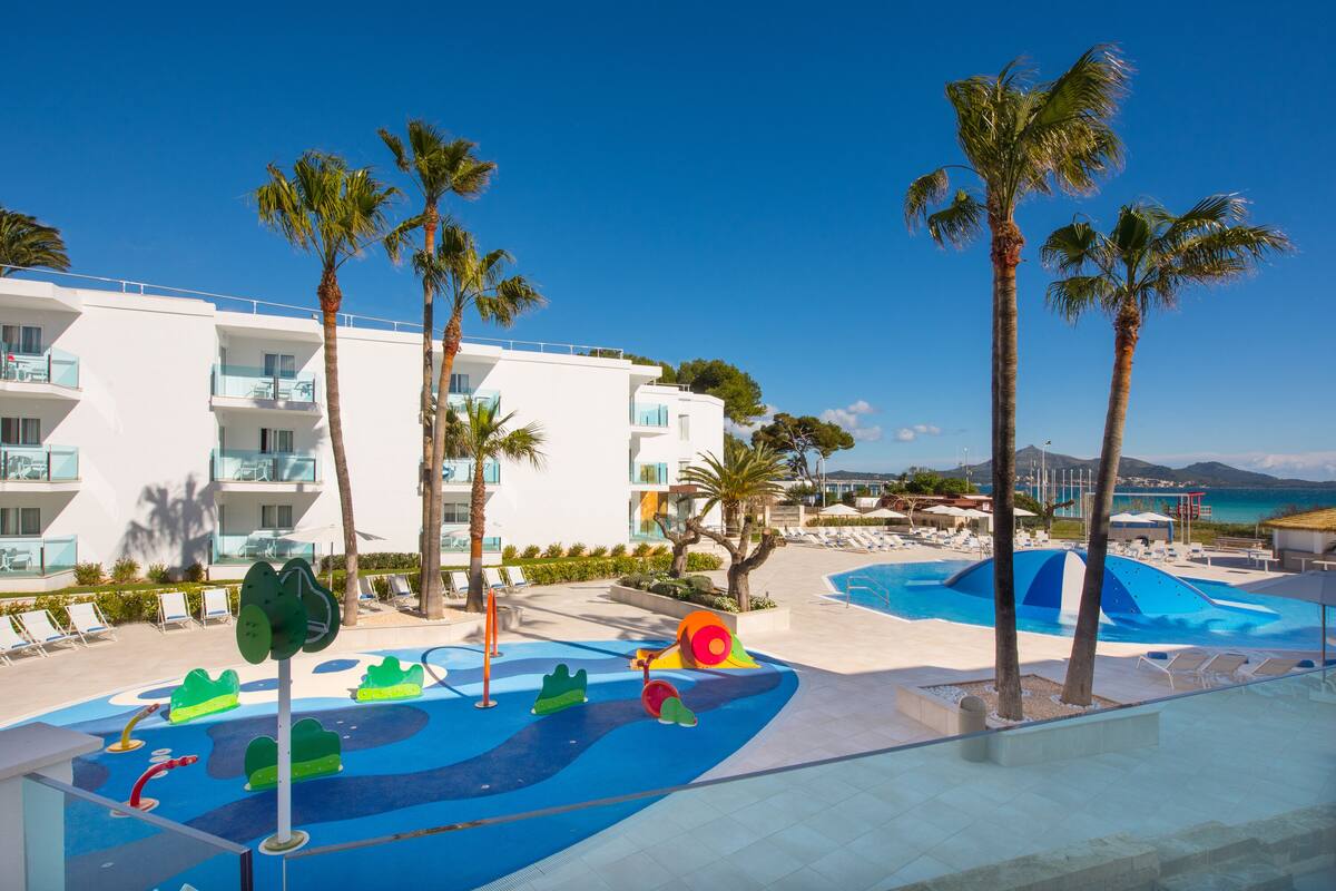 Ein Resort mit Poolbereich, Palmen und einem Gebäude mit Balkonen.