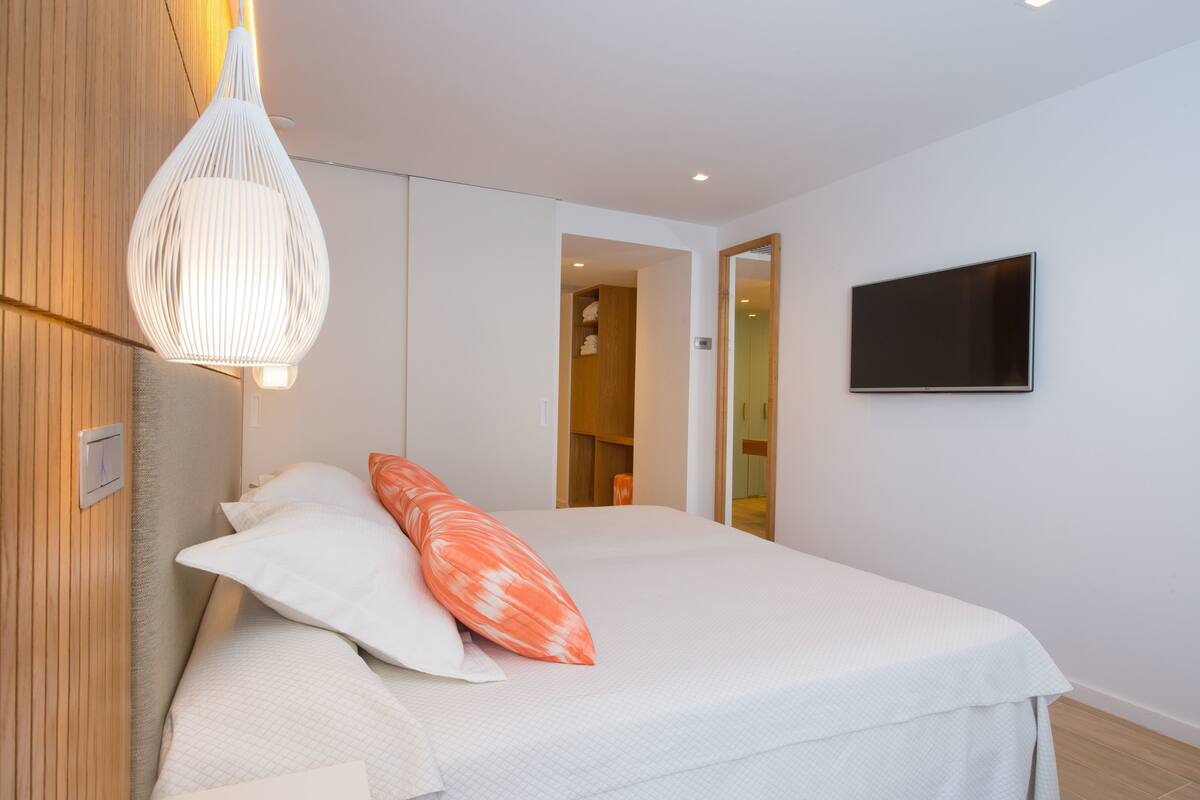 Ein modernes Schlafzimmer mit einem Bett, einem Fernseher und einer besonderen Hängelampe.