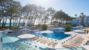 A resort pool area with sun loungers, umbrellas, and a clear view of the ocean. - Iberostar Waves Playa de Muro (Muro)