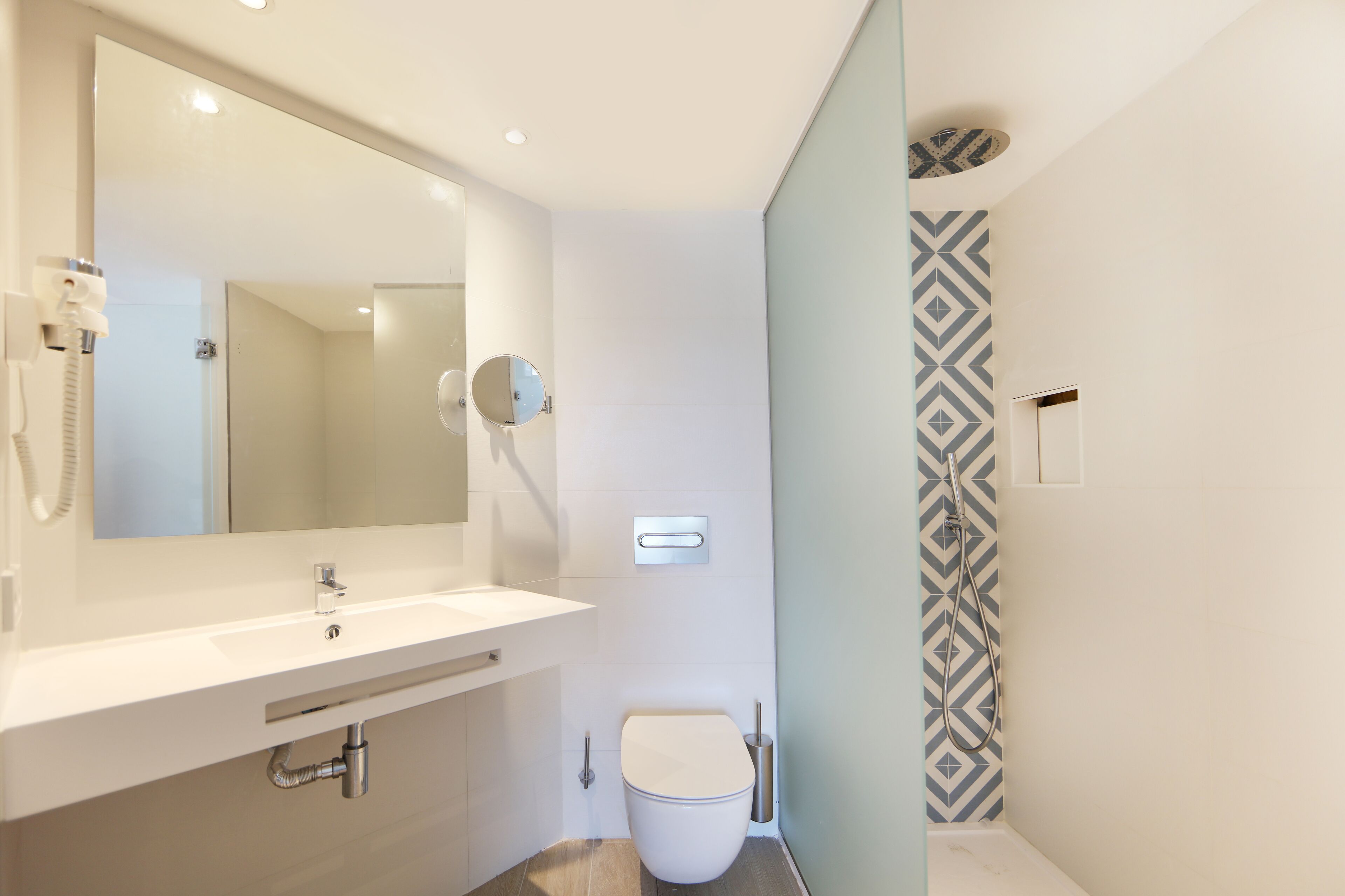 A modern bathroom with a white sink, mirror, and toilet.