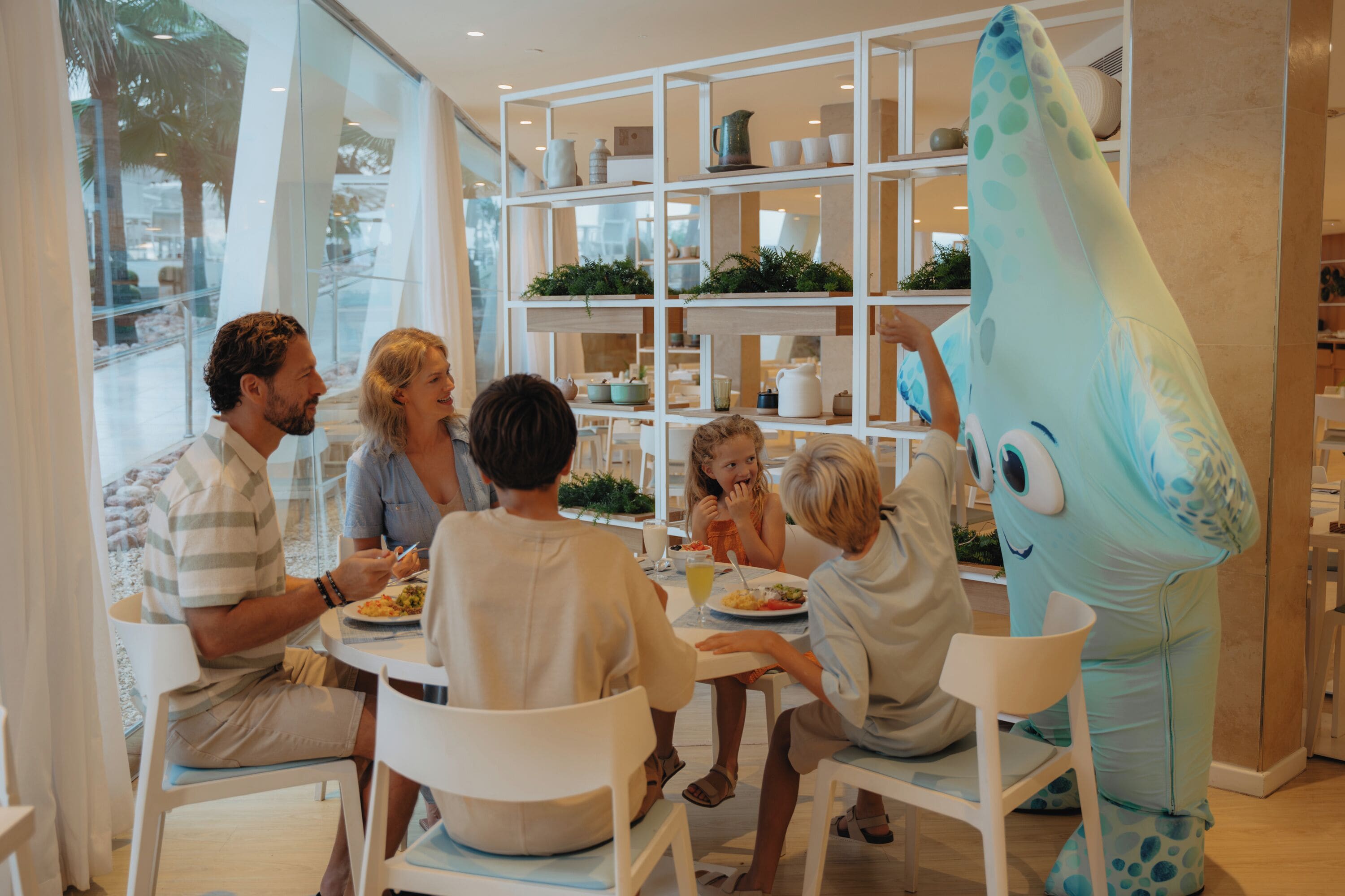 A family dining at a table with a large fish mascot.