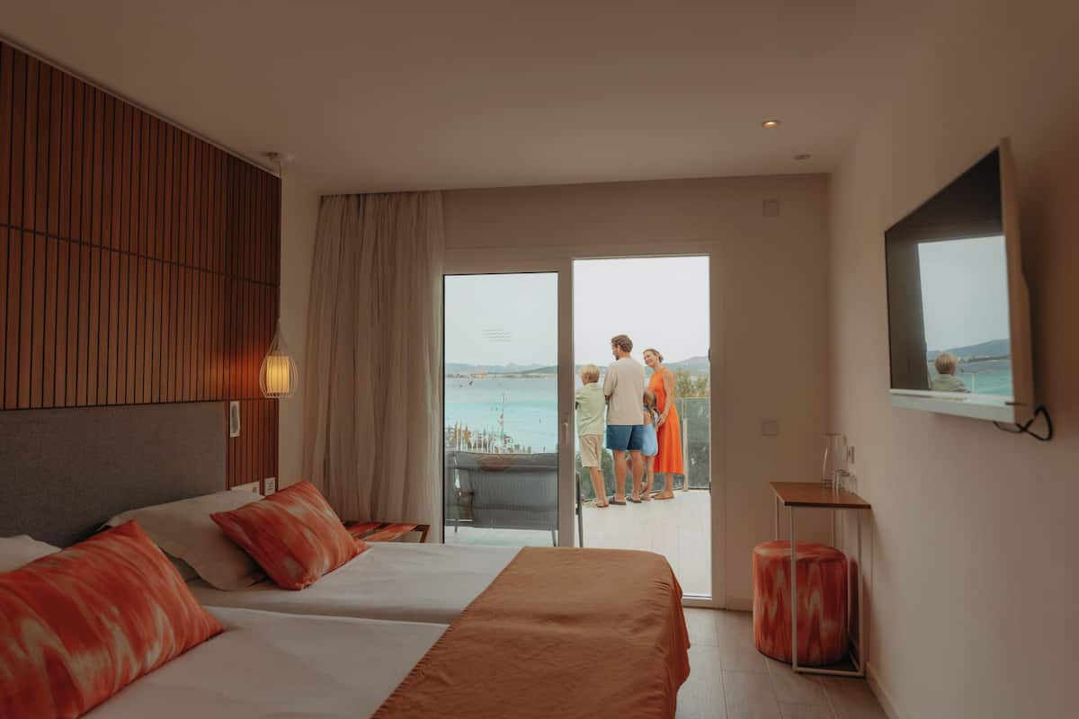 Ein Hotelzimmer mit zwei Betten, einem Balkon und Meerblick.