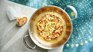 A pan with grilled chicken and a piece of bread on a marble surface.