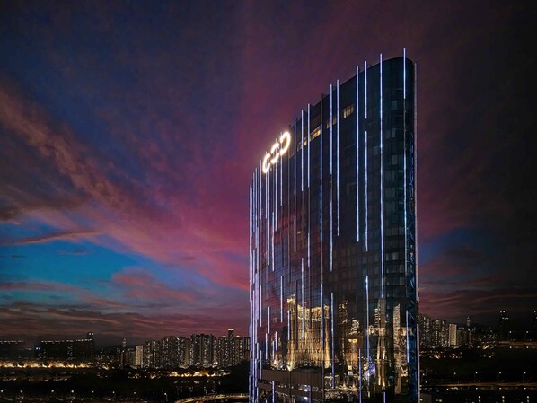 A high-rise hotel with a modern design, featuring vertical light strips and a prominent logo at the top. - City of Dreams – Nüwa Macau (Cotai)