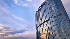 Un edificio alto y moderno de vidrio con un logotipo distintivo en la parte superior.