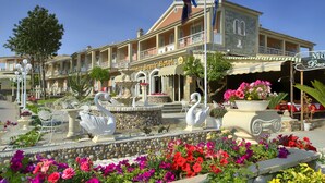 A hotel with a fountain, outdoor seating, and a flower garden. - Molfetta Beach Hotel (Corfu)
