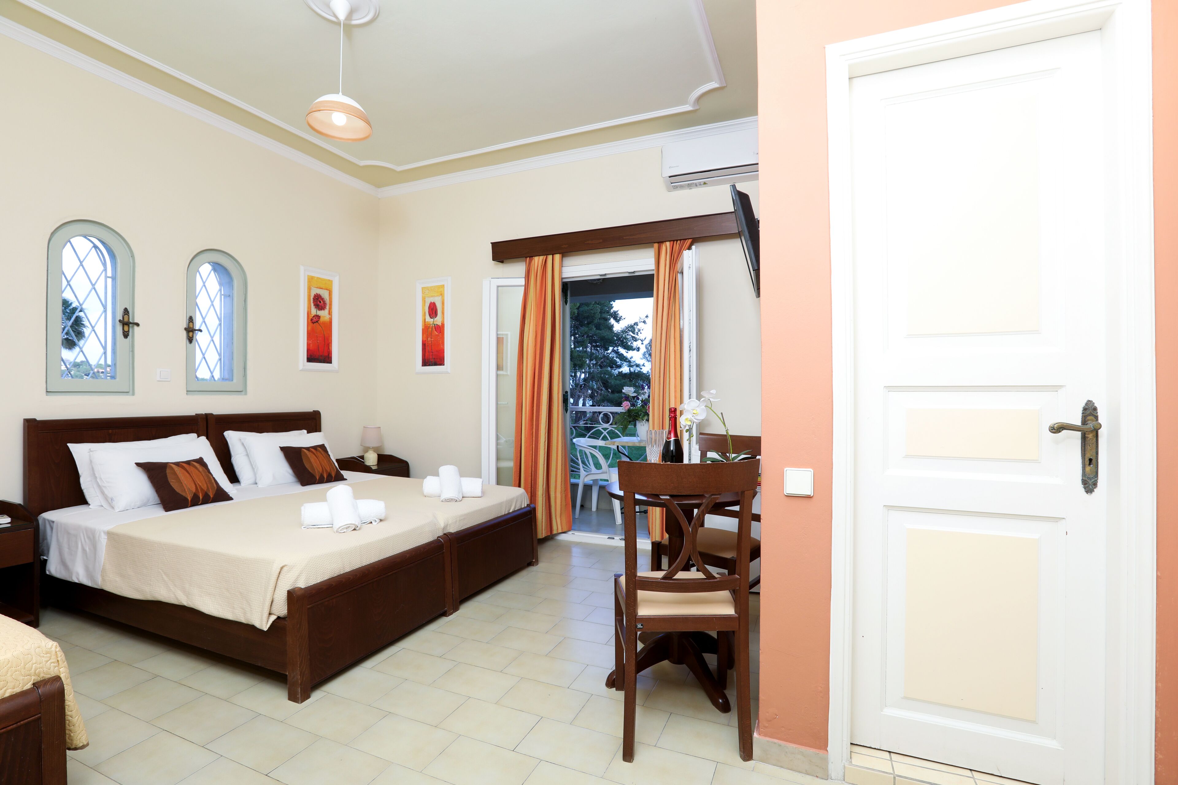 Quarto com uma cama de casal, uma cadeira de madeira, uma mesinha e uma porta.
