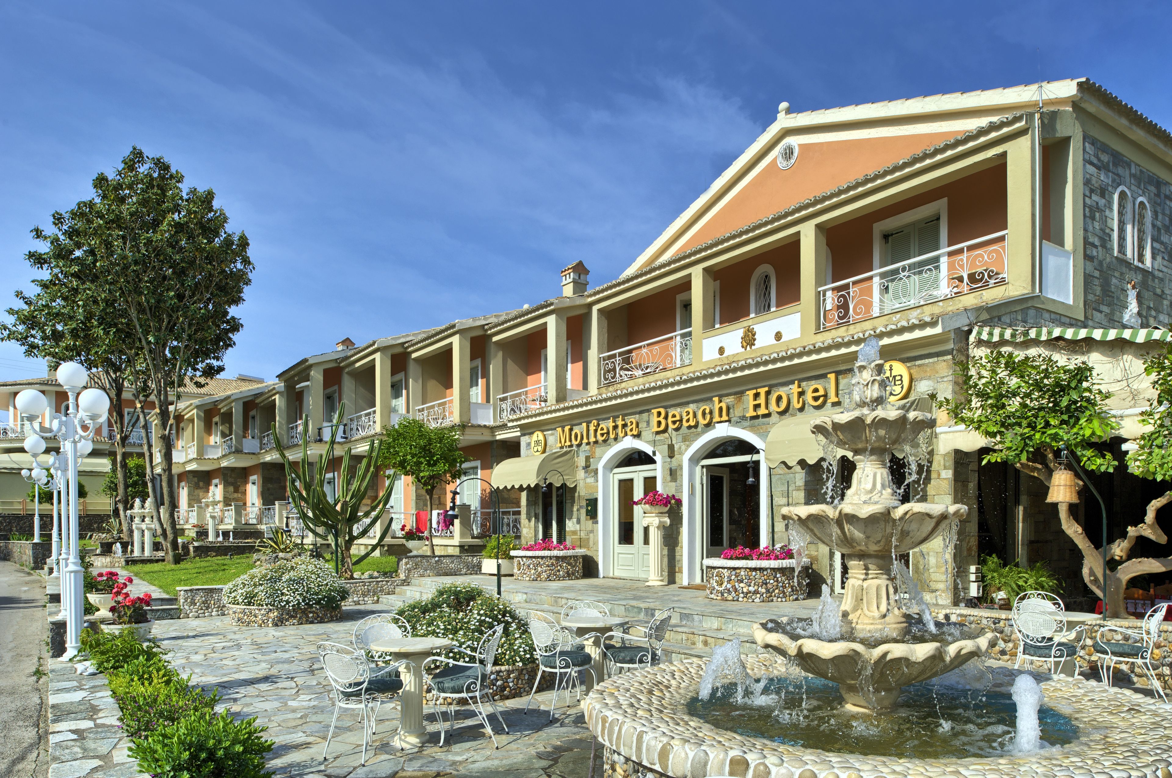 Un hôtel doté d’une fontaine, d’une terrasse et surplombant un ciel d’un bleu limpide.