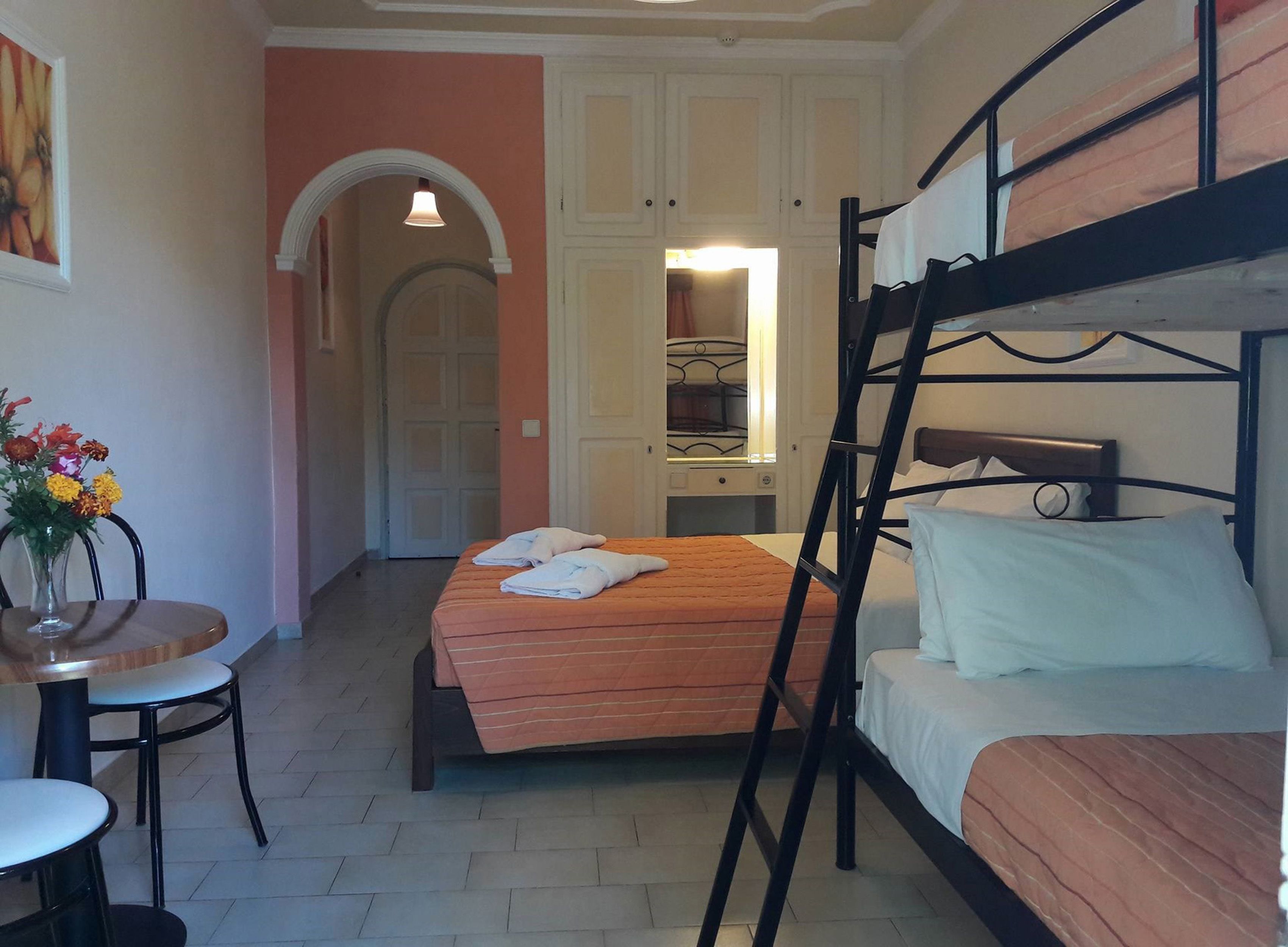 A dormitory room with bunk beds, a desk, and a chair.