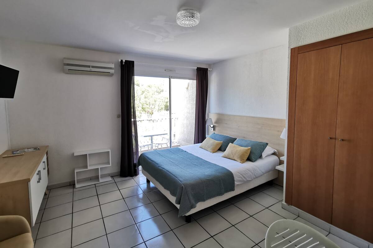 A hotel room with a bed, a desk, a chair, and a wardrobe.