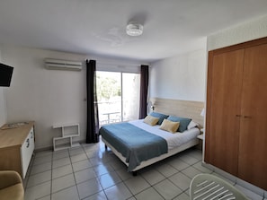 A hotel room with a bed, a desk, a chair, and a wardrobe.