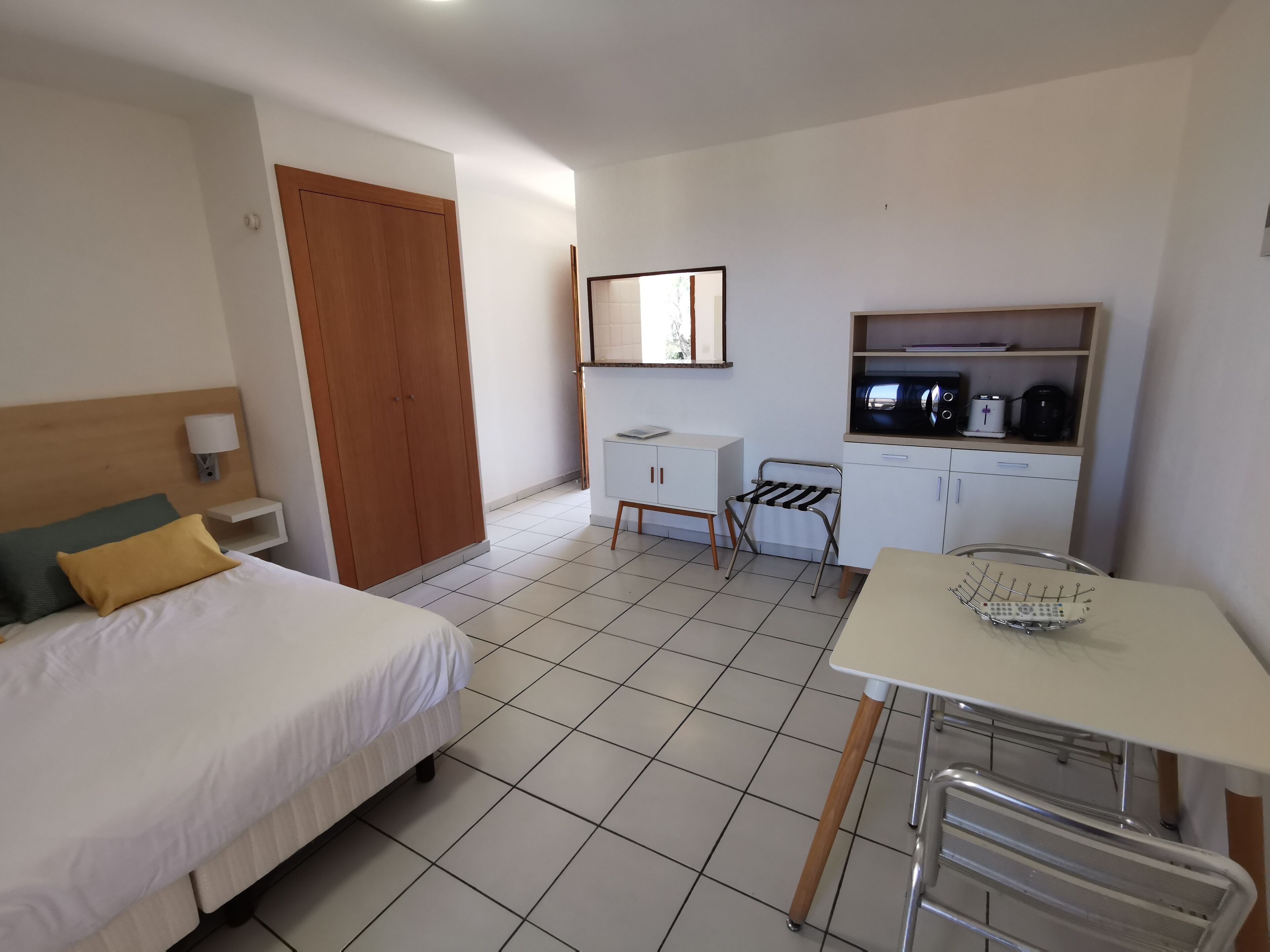 A hotel room with a bed, a desk, a chair, a microwave, and a small cabinet.