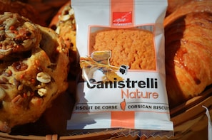 A package of Canistrelli Nature biscuits and a loaf of bread with visible nuts and seeds.