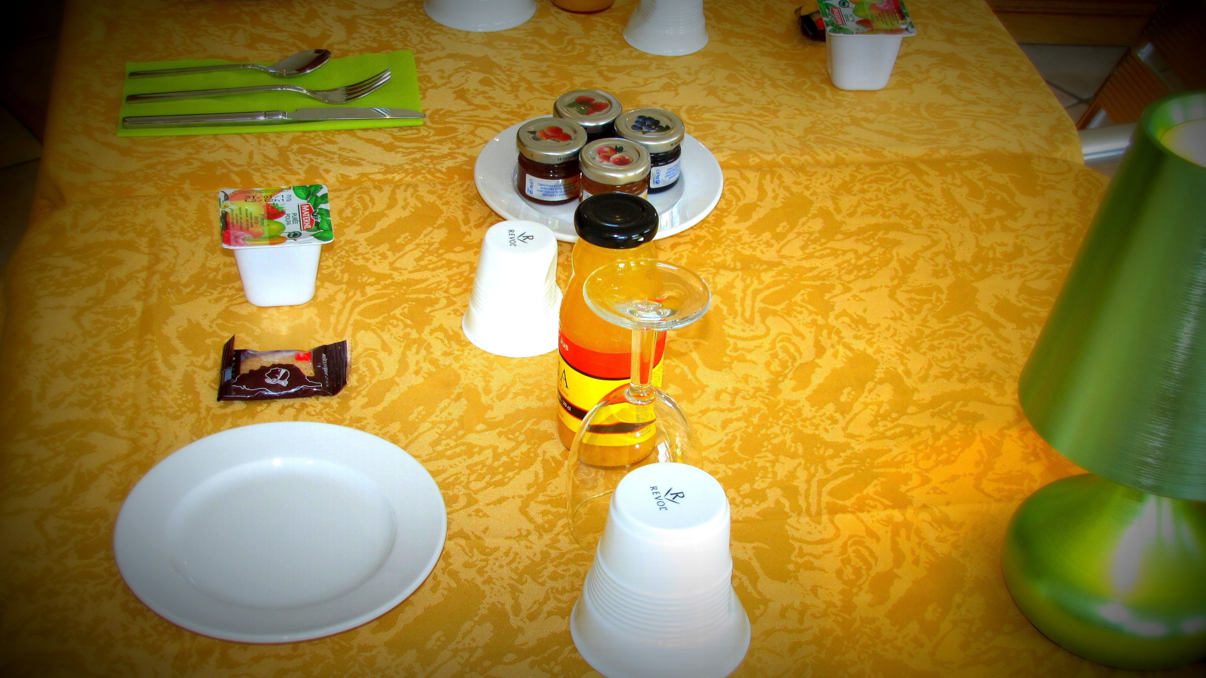 A table set with plates, cutlery, a glass, and condiments.