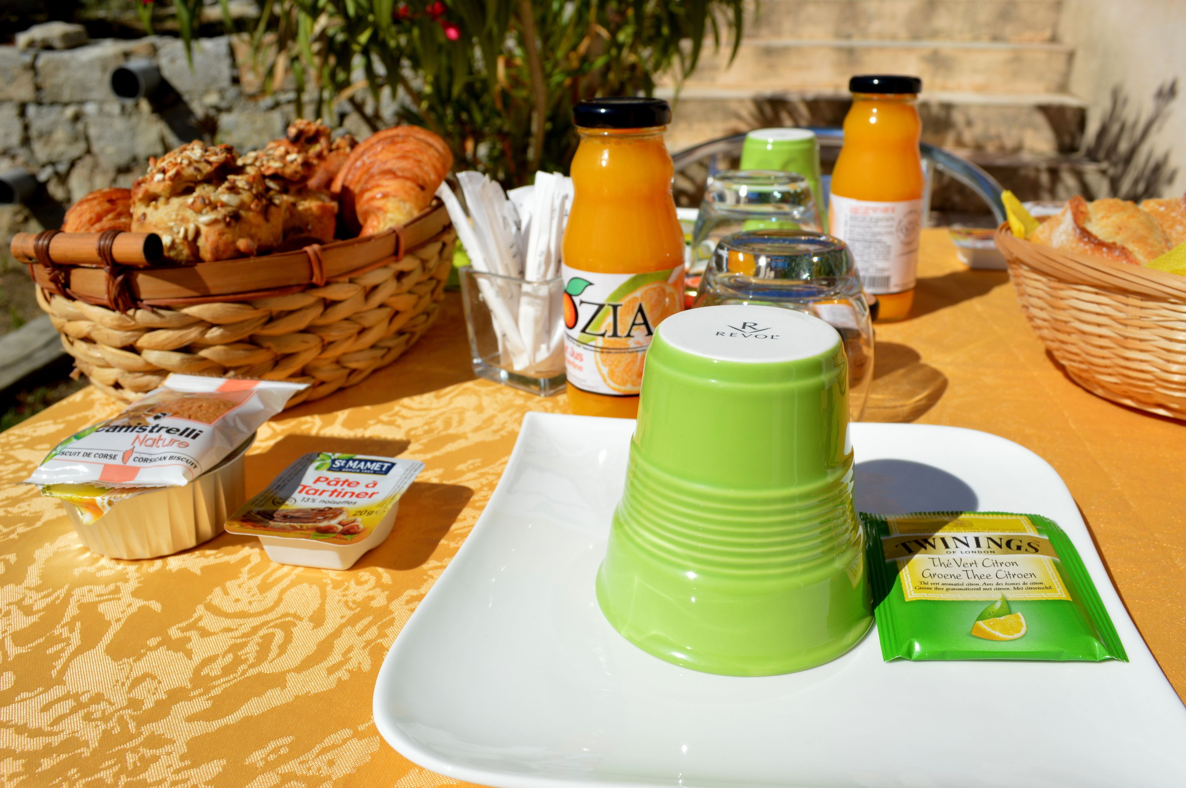 A breakfast table with croissants, orange juice, and a green beverage.
