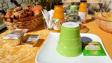 A breakfast table with croissants, orange juice, and a green beverage.