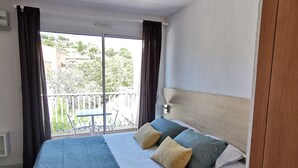 Une chambre d’hôtel avec un grand lit, une vue sur un balcon et une fenêtre avec des rideaux.