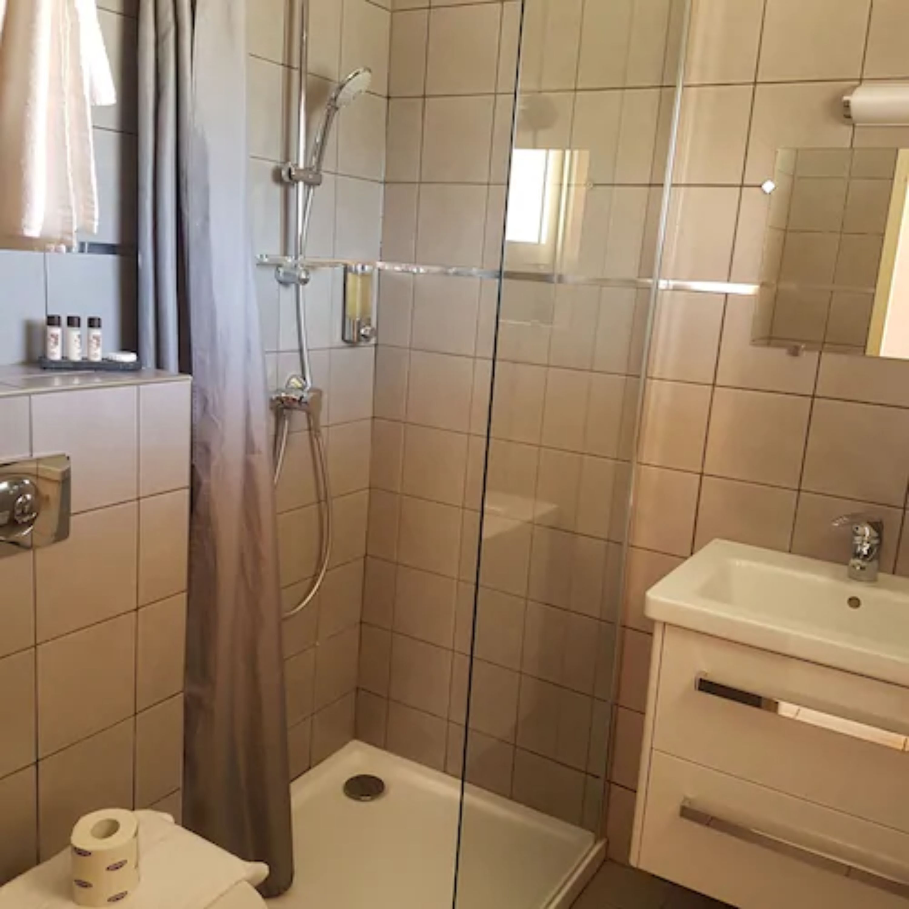 A bathroom with a glass-enclosed shower, a sink, and a toilet.