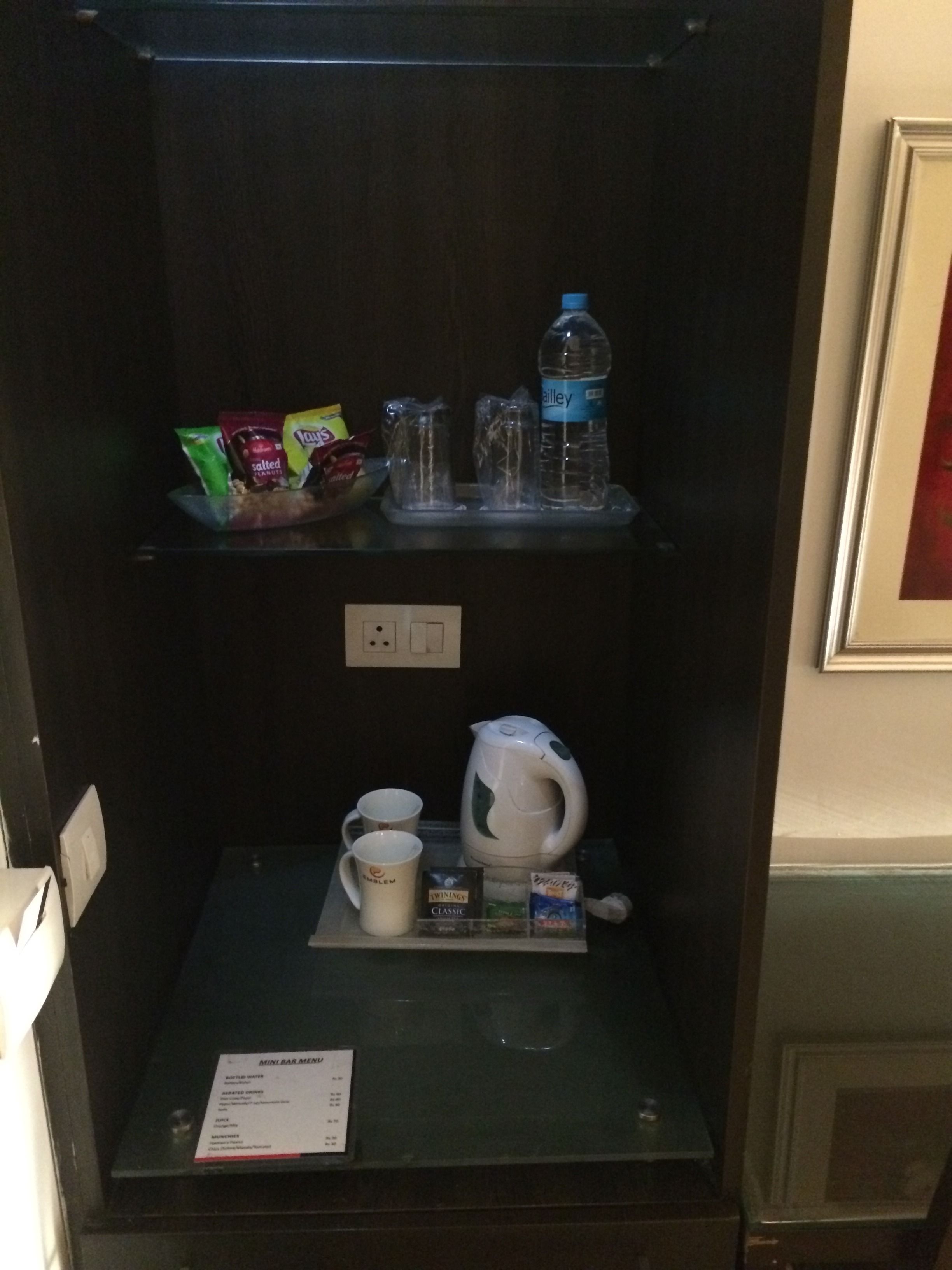 Un minibar con aperitivos, agua embotellada y una tetera.