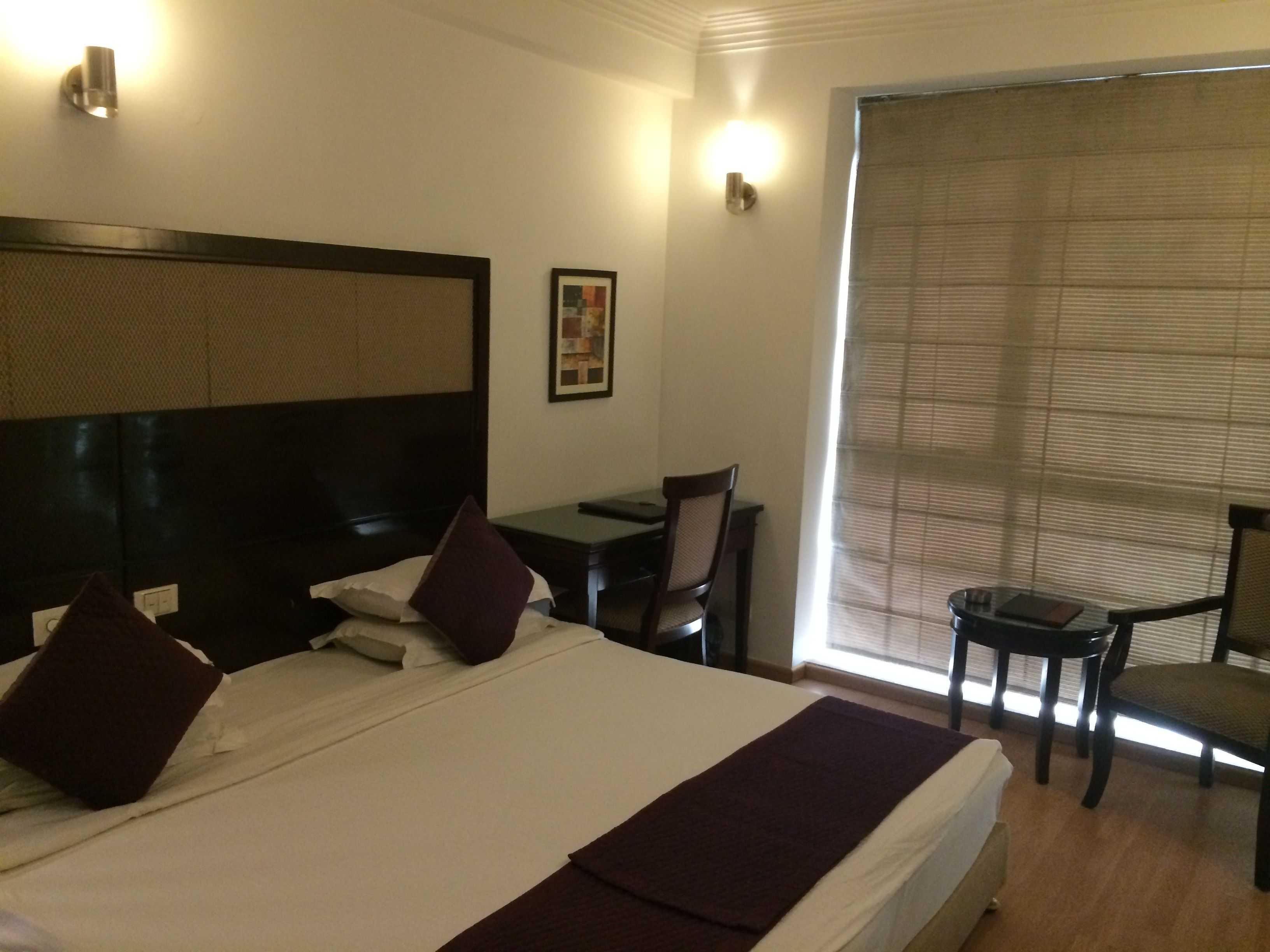 Quarto de hotel com uma cama grande, uma mesa e uma cadeira.
