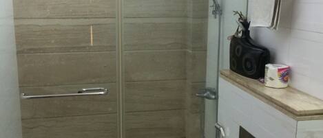 Un baño con ducha de vidrio, inodoro y lavamanos.
