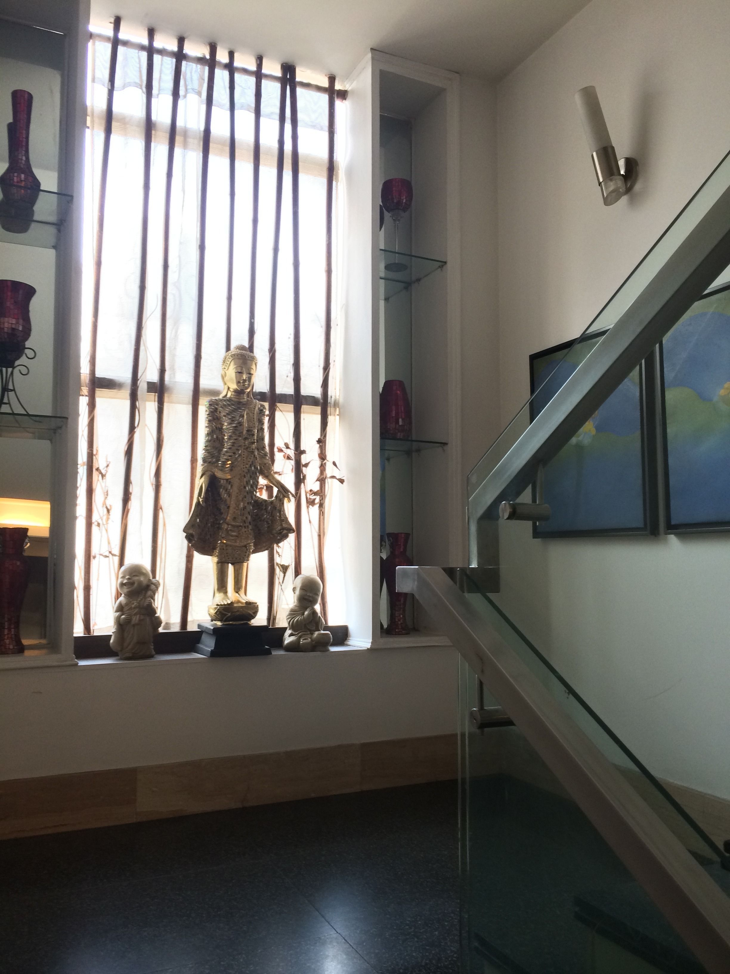 A room with a large window, a statue, and a staircase.