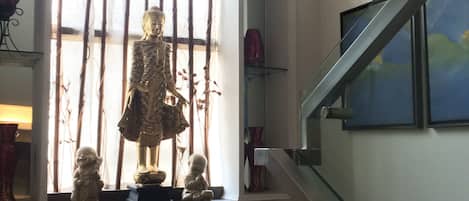 A room with a large window, a statue, and a staircase.