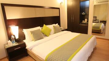 A hotel room with a large bed, a nightstand, a wardrobe, and a mirror.