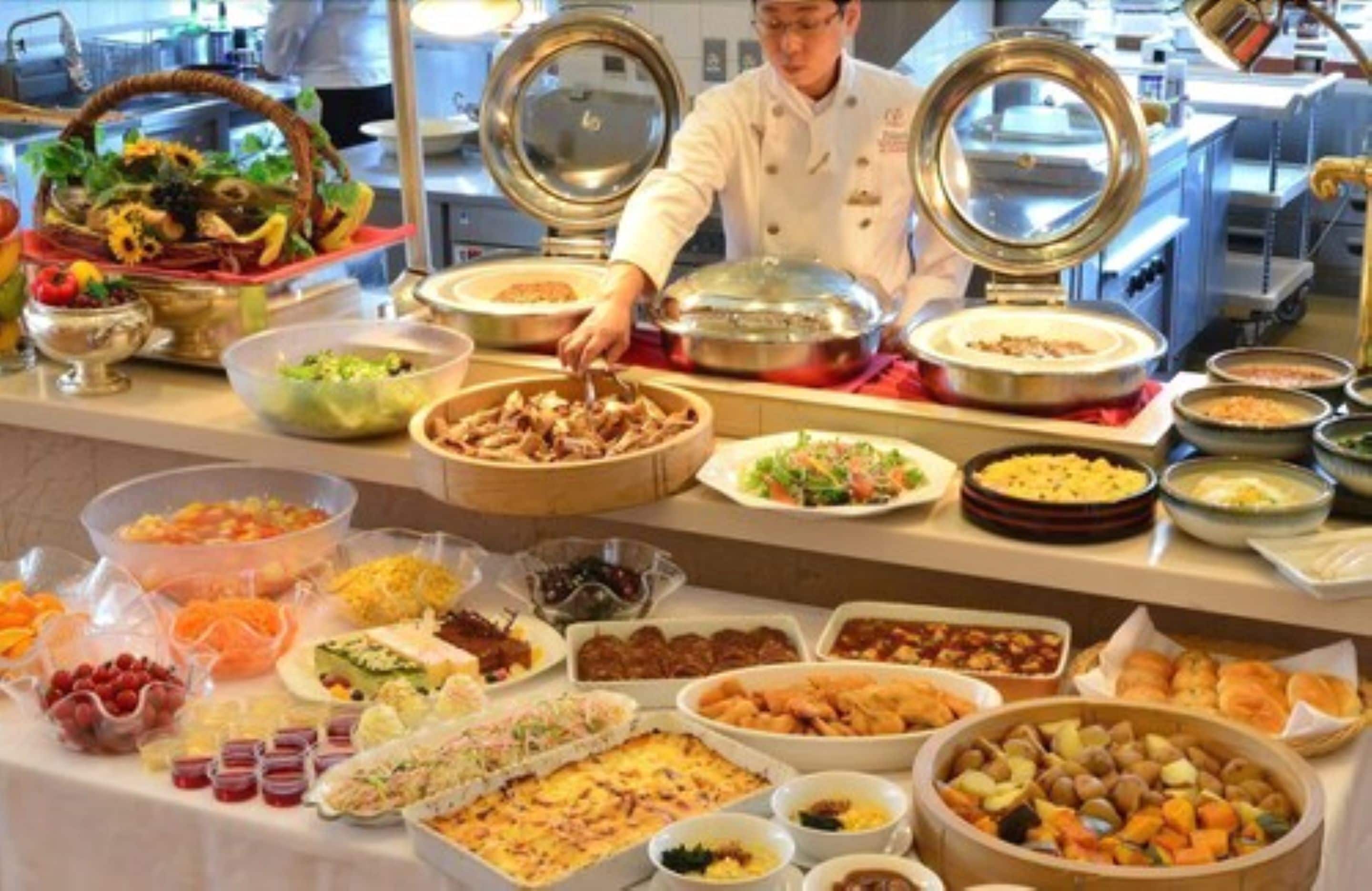 Un bufé con diversos platos y un chef sirviendo comida.